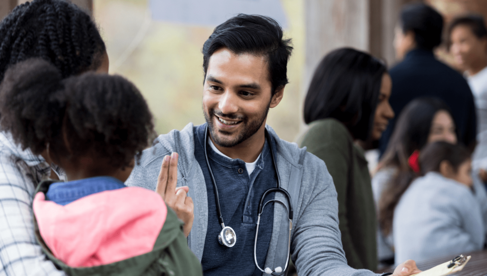 Young male doctor volunteering and looking after mother and young daughter