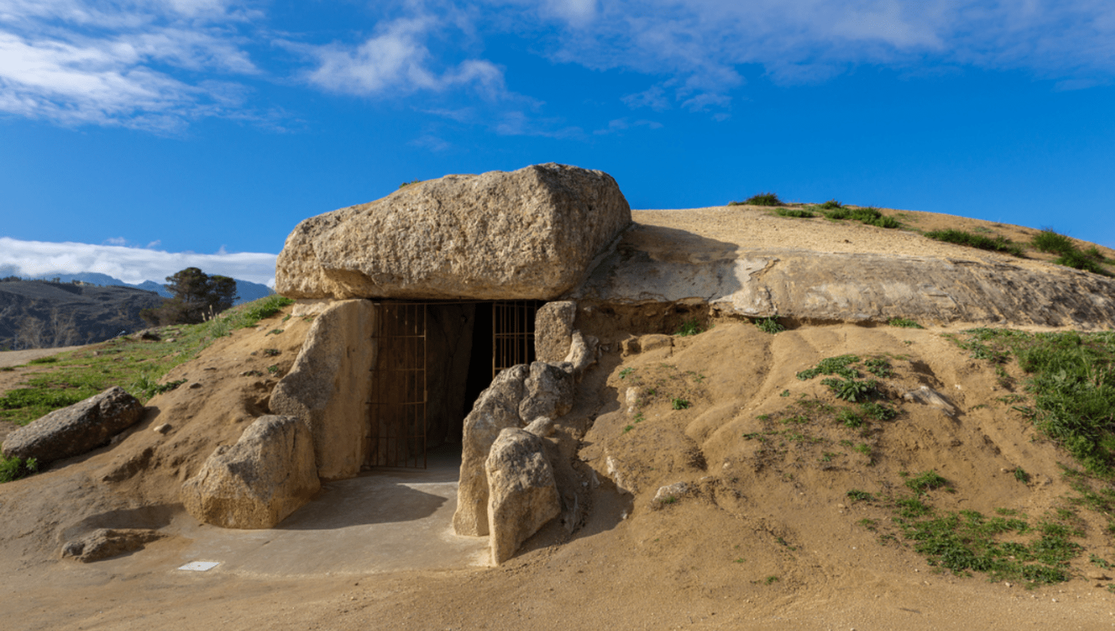 Rock entryway to large dome covered by earth