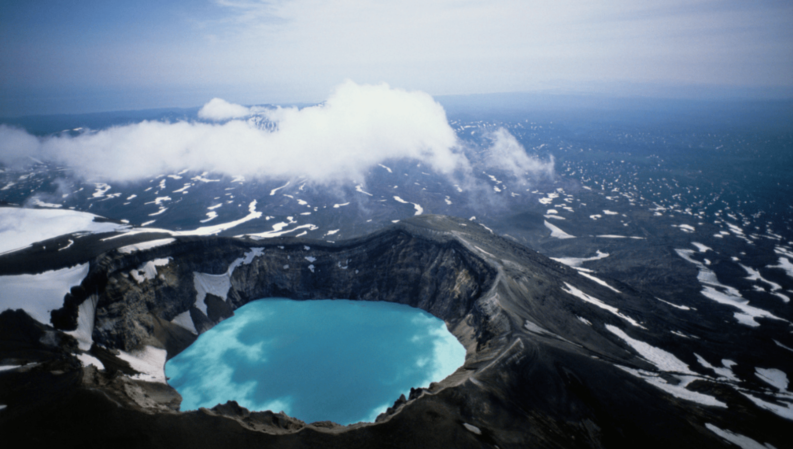 large crater in volcano filled with bright blue water