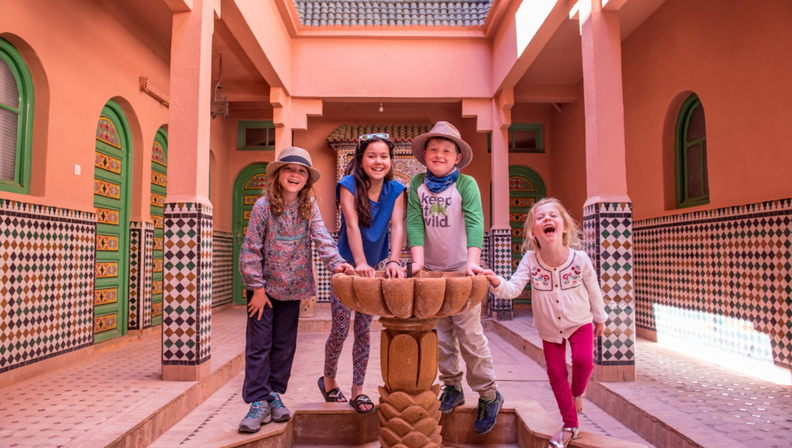 four children standing around water feature