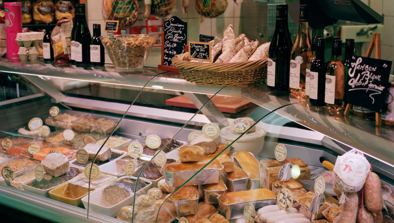 Deli with lots of different meats, cheeses and bread in cabinet and on counter