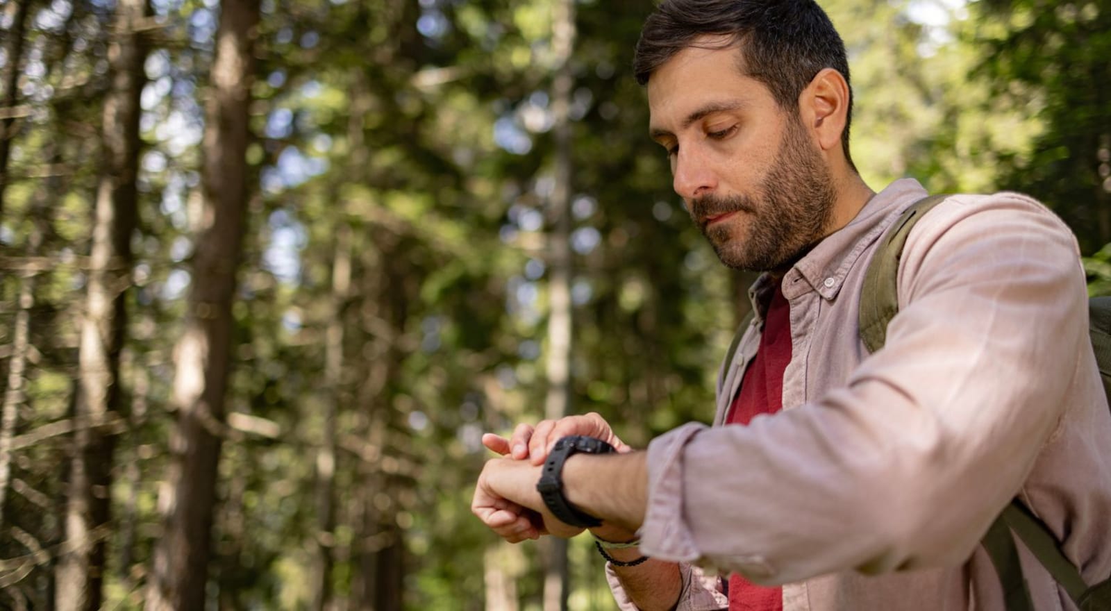 man checking his watch while hiking in the woods