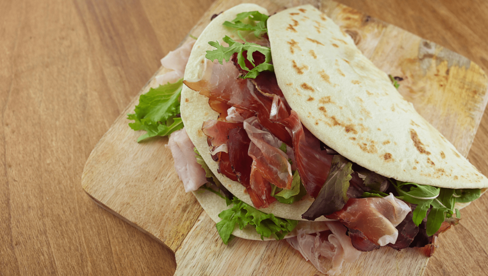 flatbread folded in half and filled with thinly sliced meat and lettuce