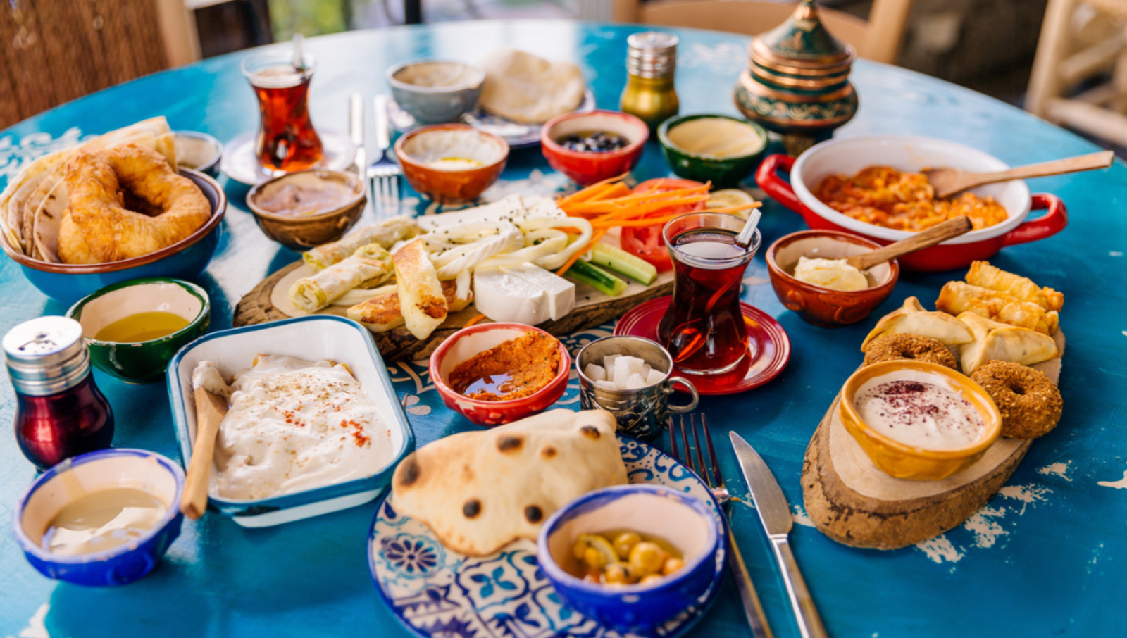 spread of dips, bread, cheese, vegetables, and tea on table in turkey