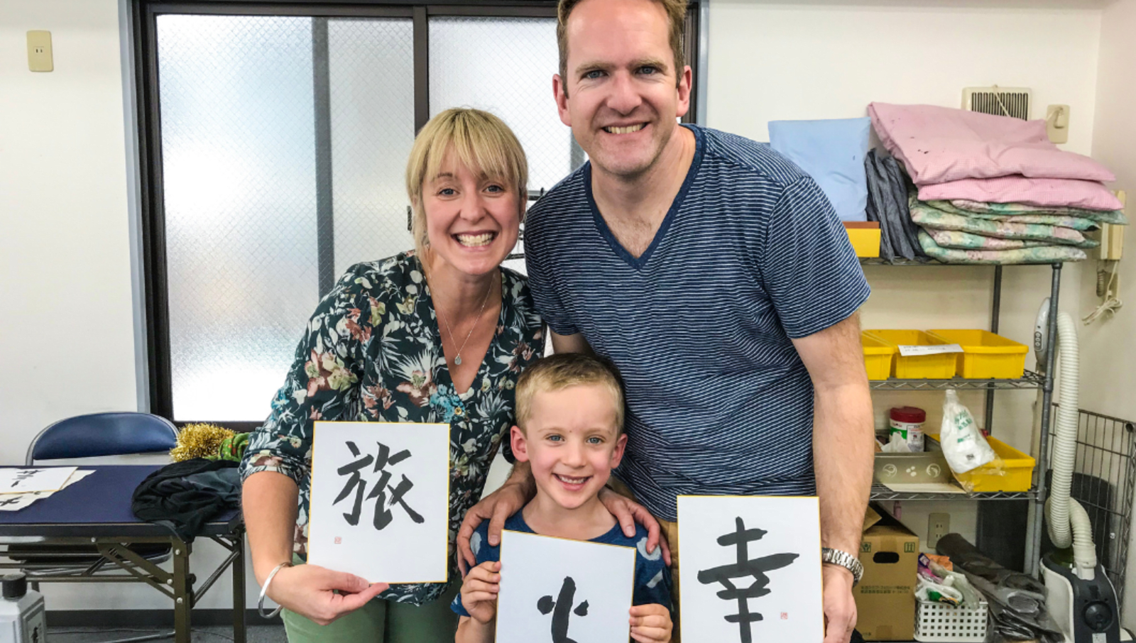 Parents and son holding paper with japanese calligraphy