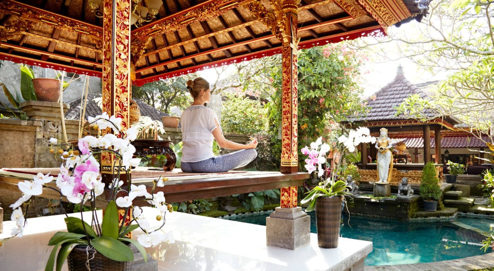 lady doing yoga by a pool in hut in bali