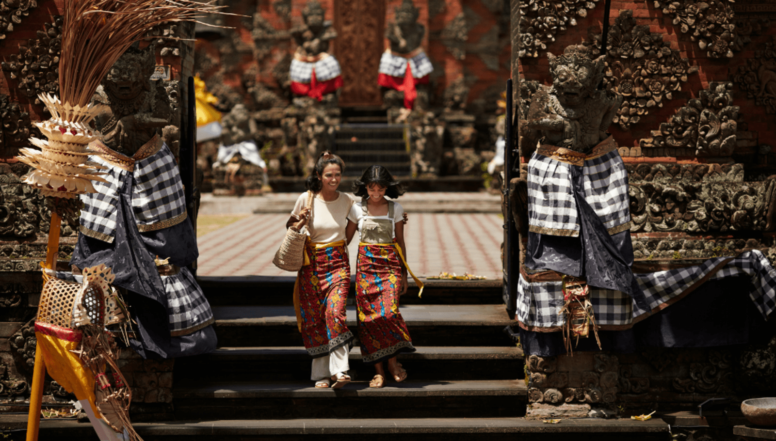 Adult and child walk down the stairs of a temple in bali 