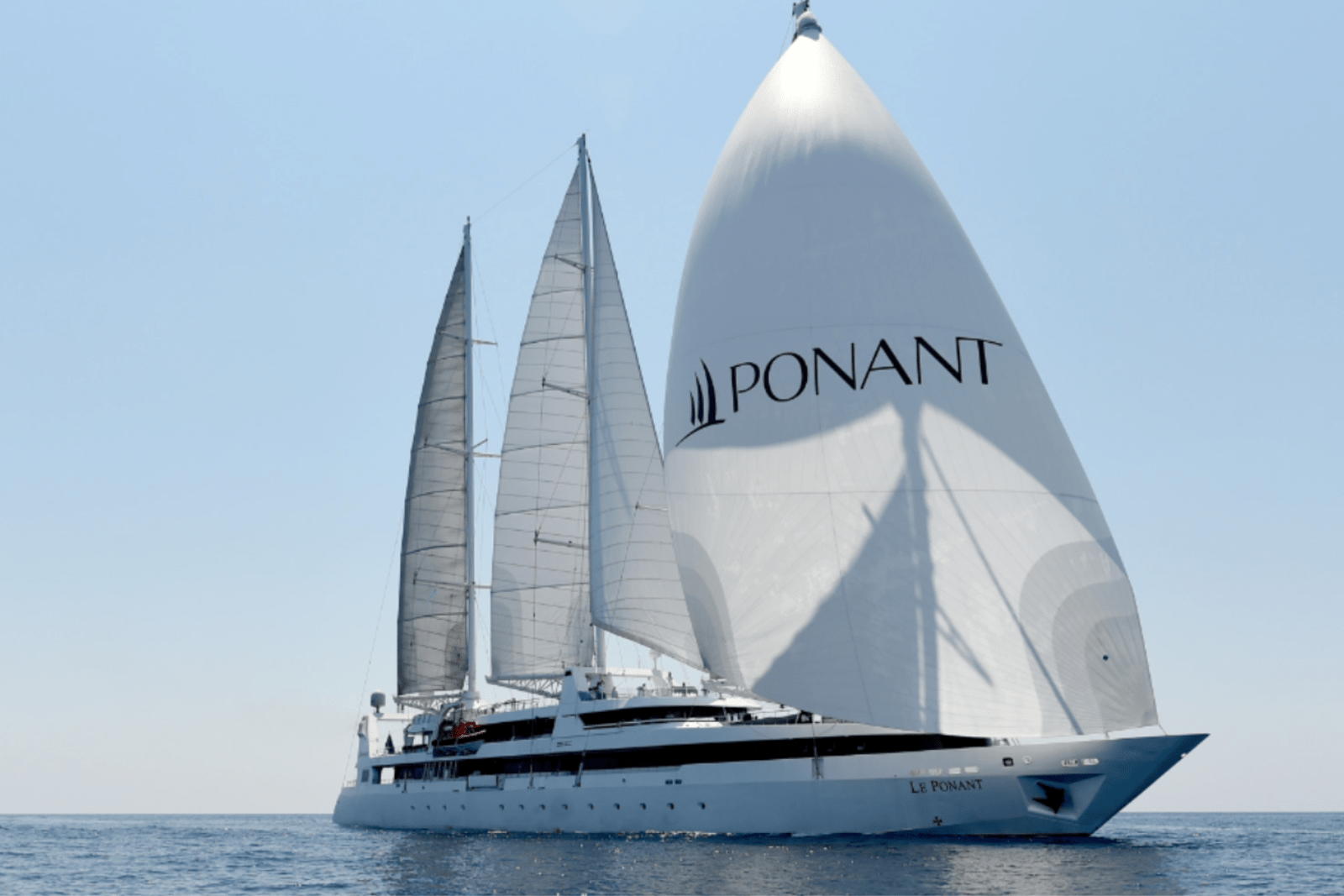 A large yacht with the word 'PONANT" emblazoned on its spinnaker