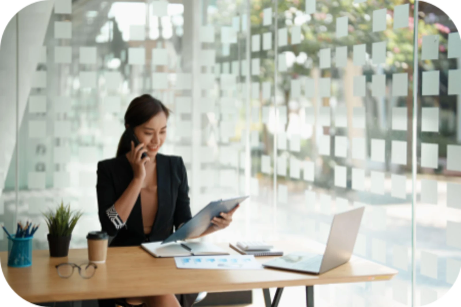 Woman on phone sitting at a desk with a laptop