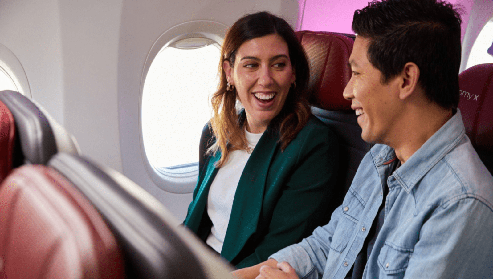 two people sitting on plane smiling at each other