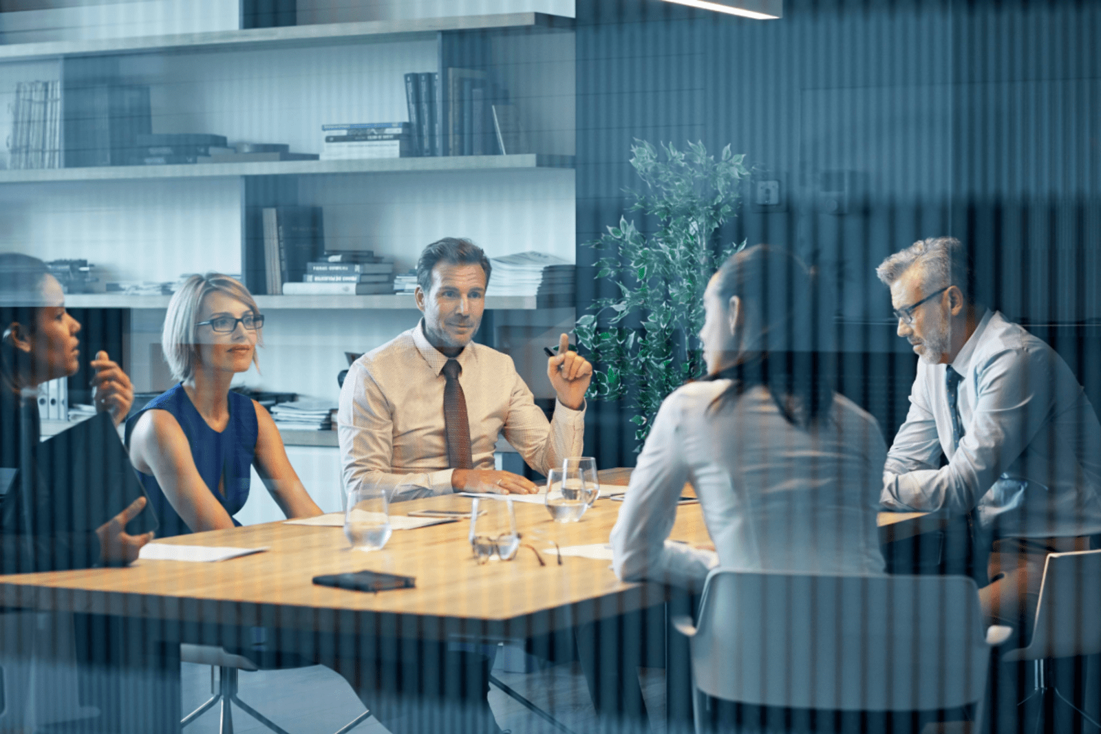 business men and women sitting around a table in a small office