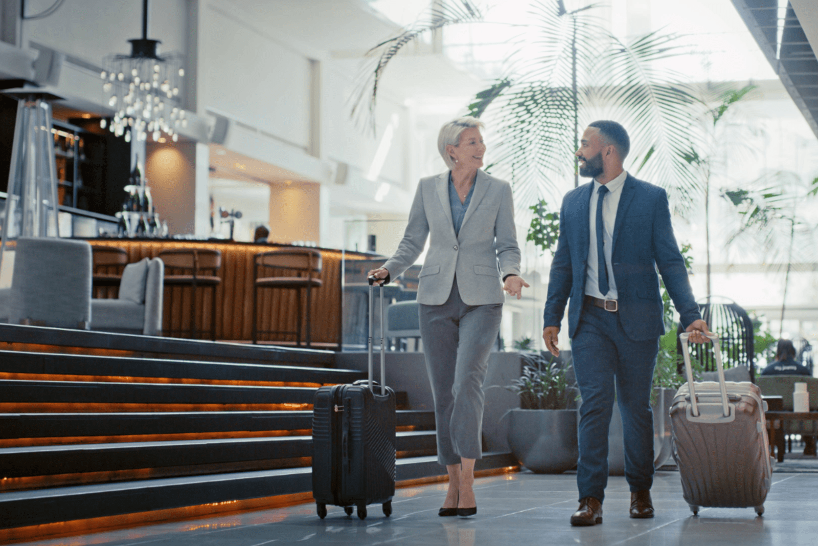 two business people walking through a hotel lobby with suitcases