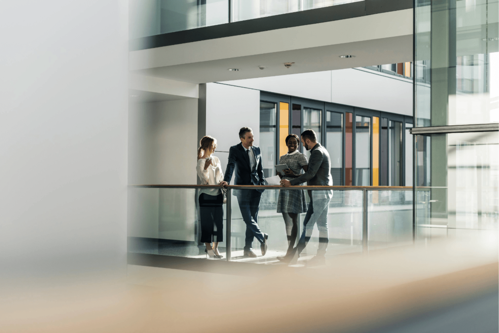 four business people standing near balcony on walkway in office 