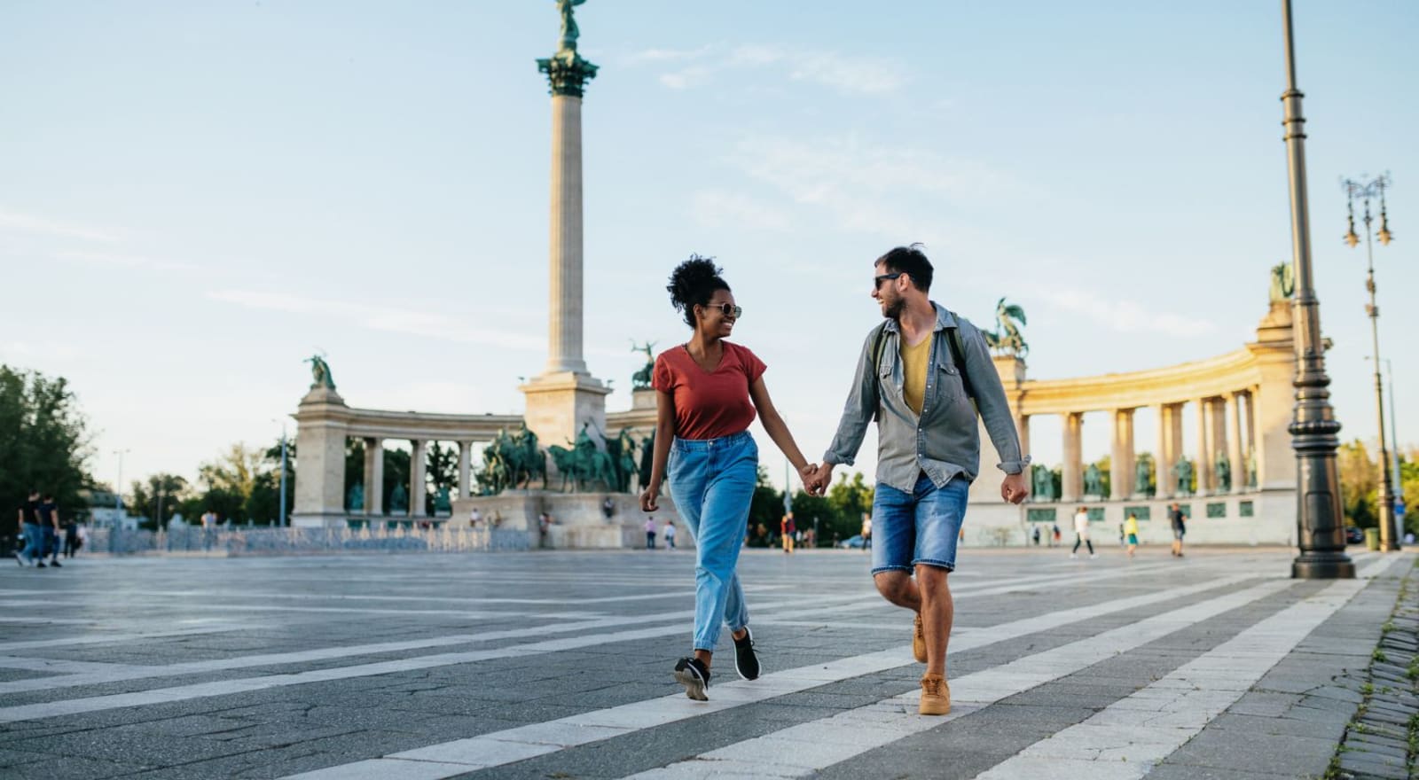 couple holding hands and walking through square in budapest