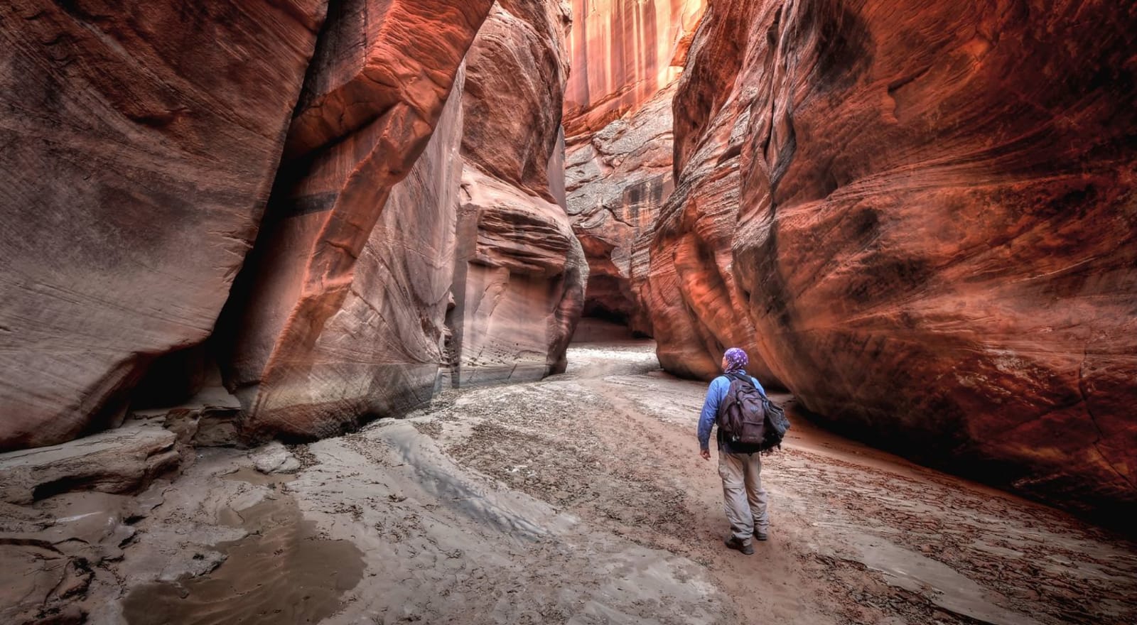 woman hiking between orange rock formations 