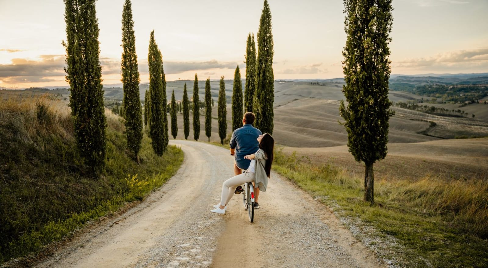 couple riding bike down hill in tuscany