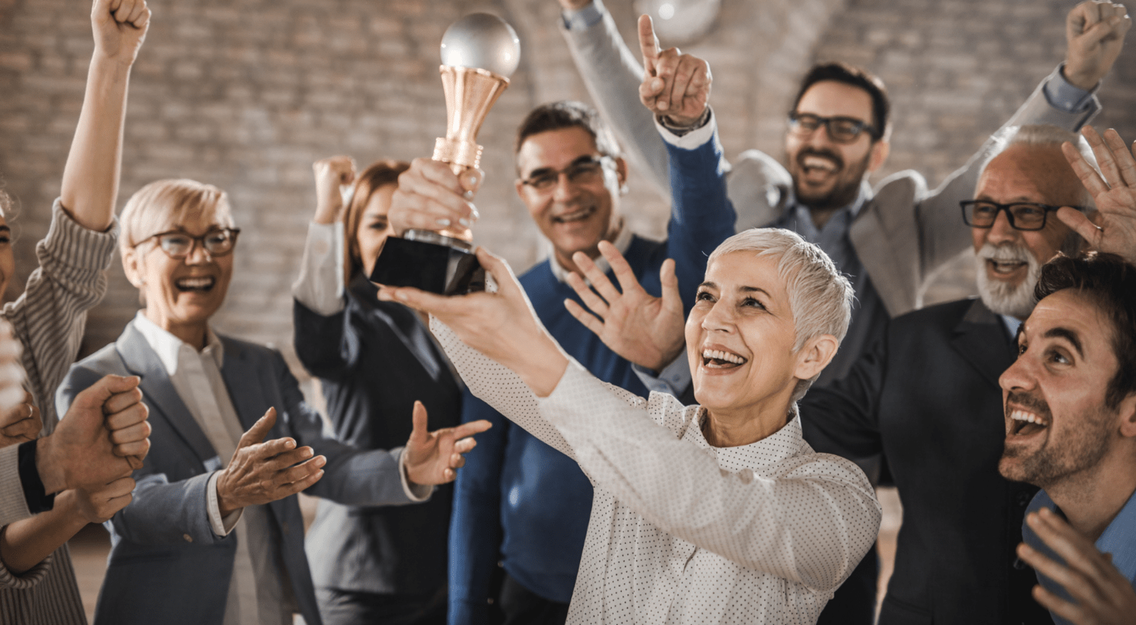 business people cheering and holding up trophy