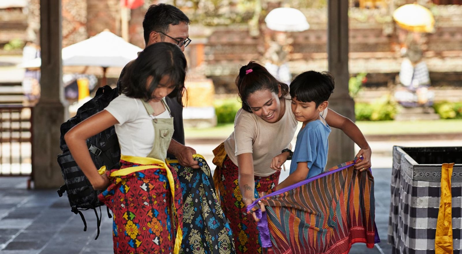 family getting sarongs put on at temple 