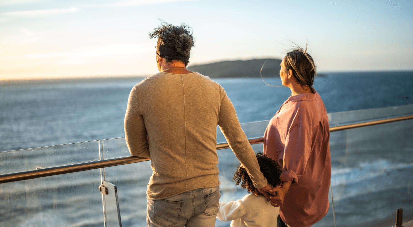 Husband, wife and daughter looking out to sea from cruise ship