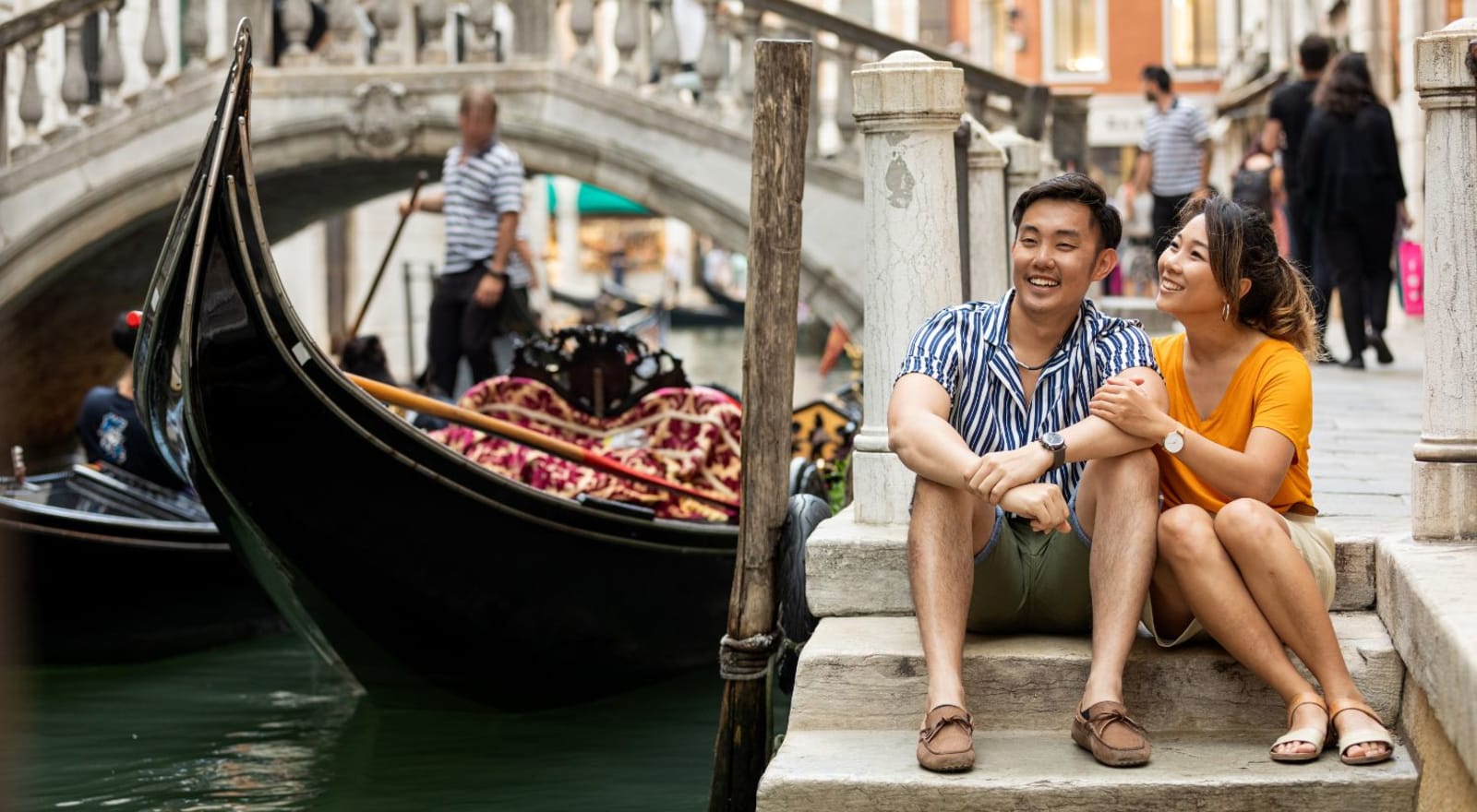 couple sitting on steps beside canal in venice