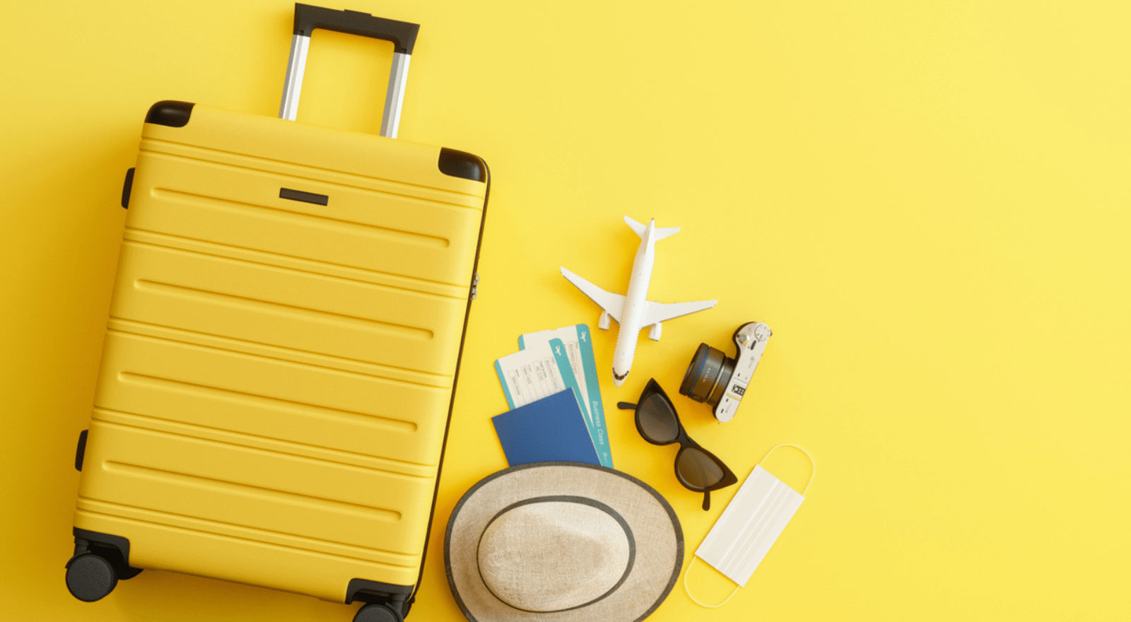 luggage on yellow background with other travel objects