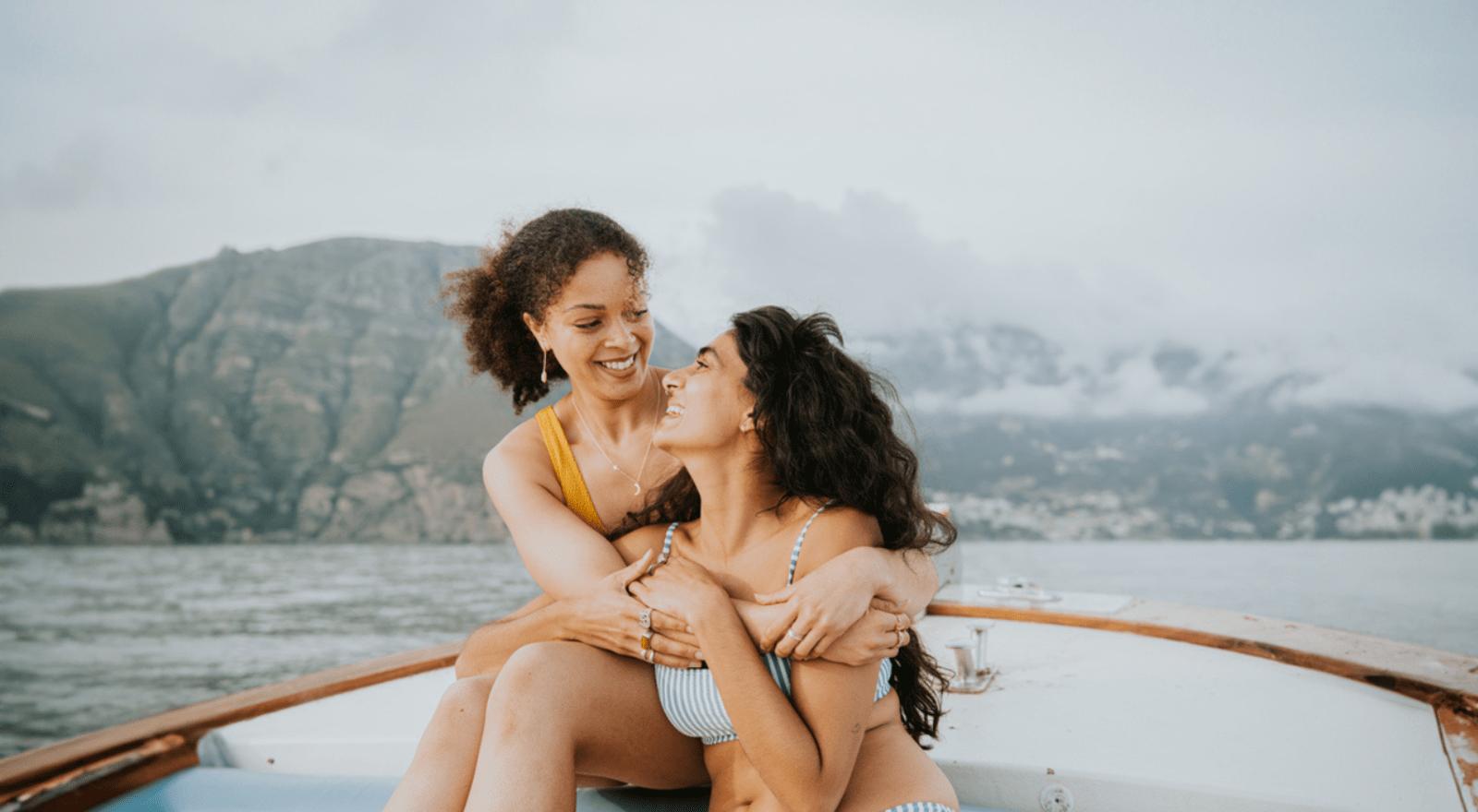 two women embracing and smiling on a boat ride in italy 