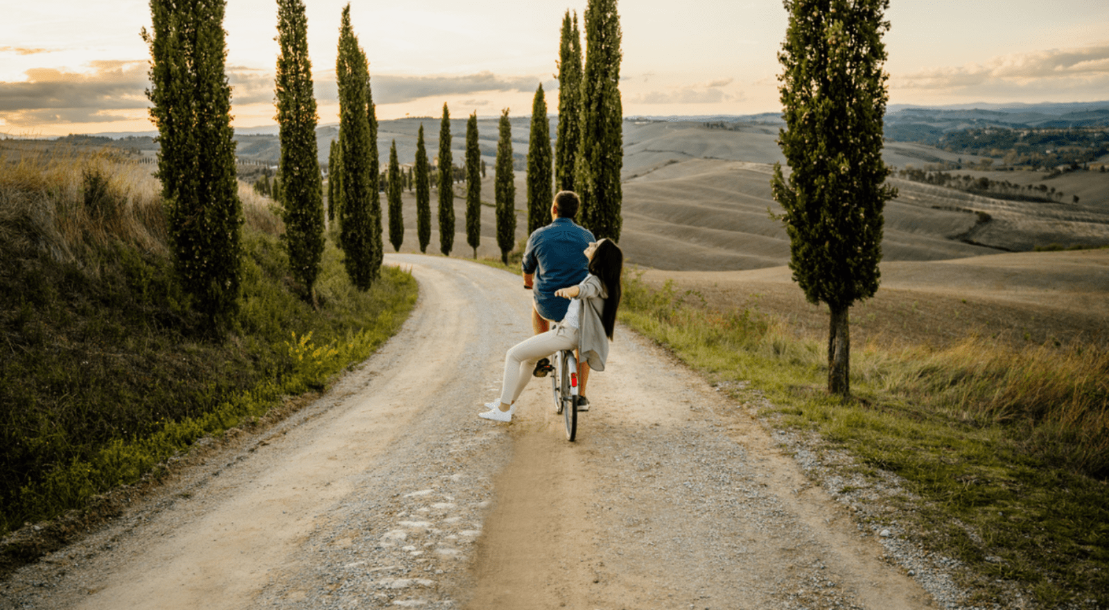 couple riding bike together down hill in tuscany