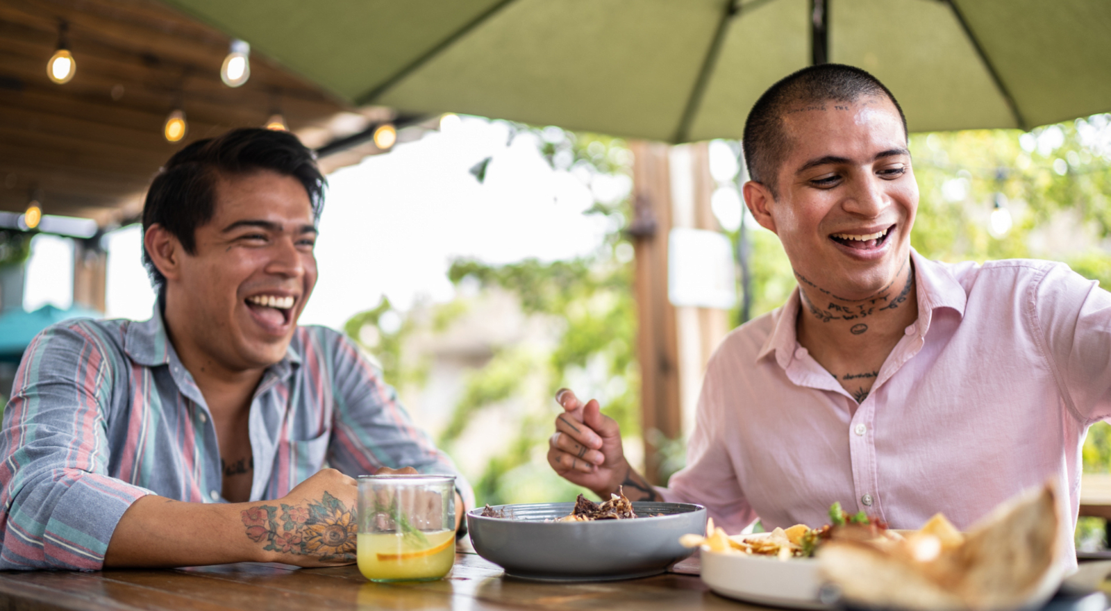 two men eating mexican food together and smiling