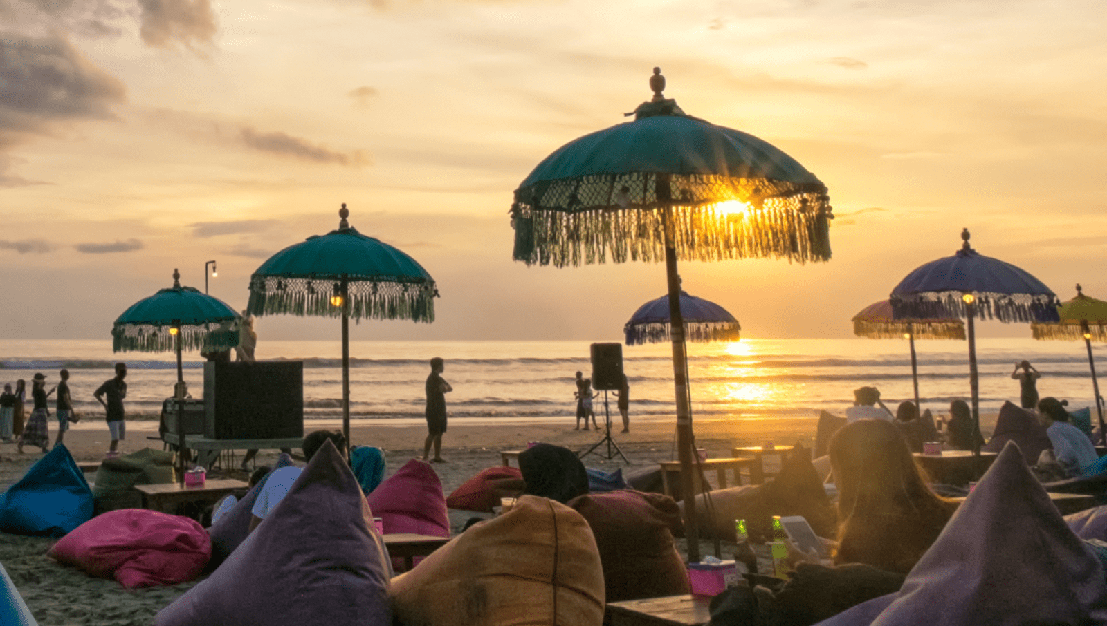 people watch sunset under umbrellas at Kuta Beach