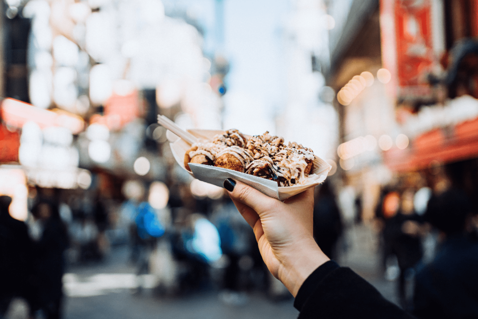 A traveller holds a tray of takoyaki in Japan