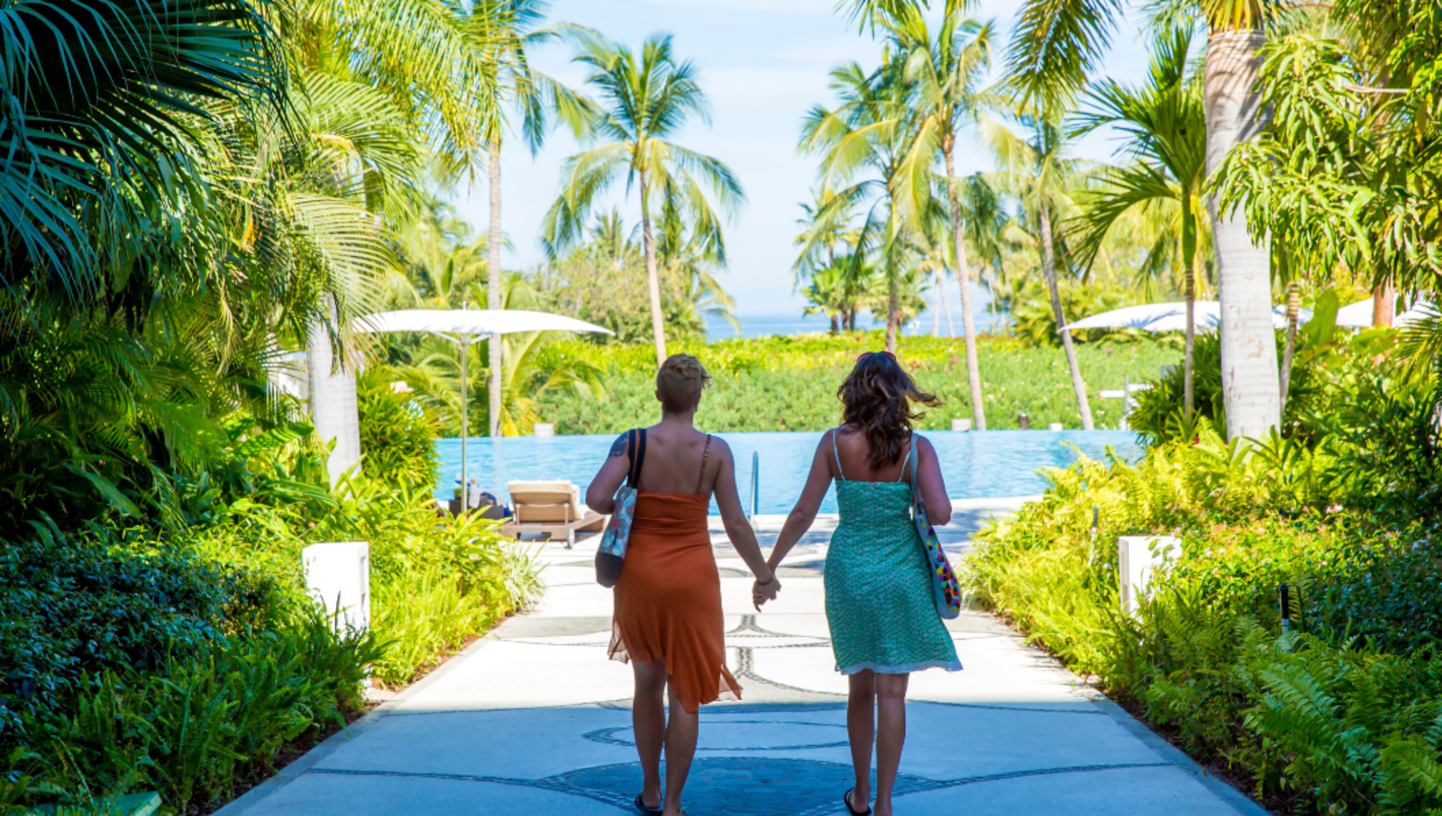 couple walking to pool holding hands in a tropical resort 