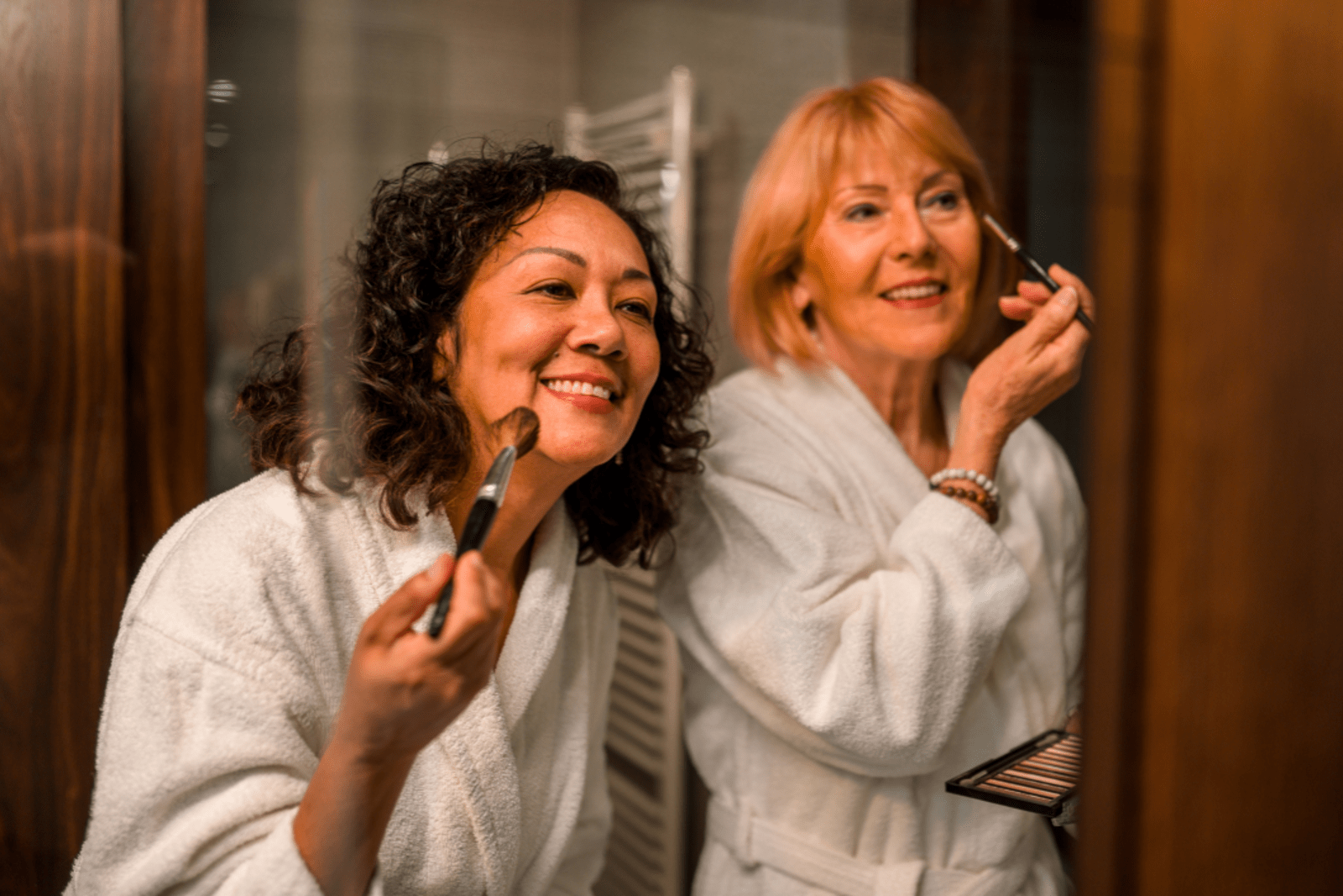 Two women putting on makeup in a cruise ship bathroom