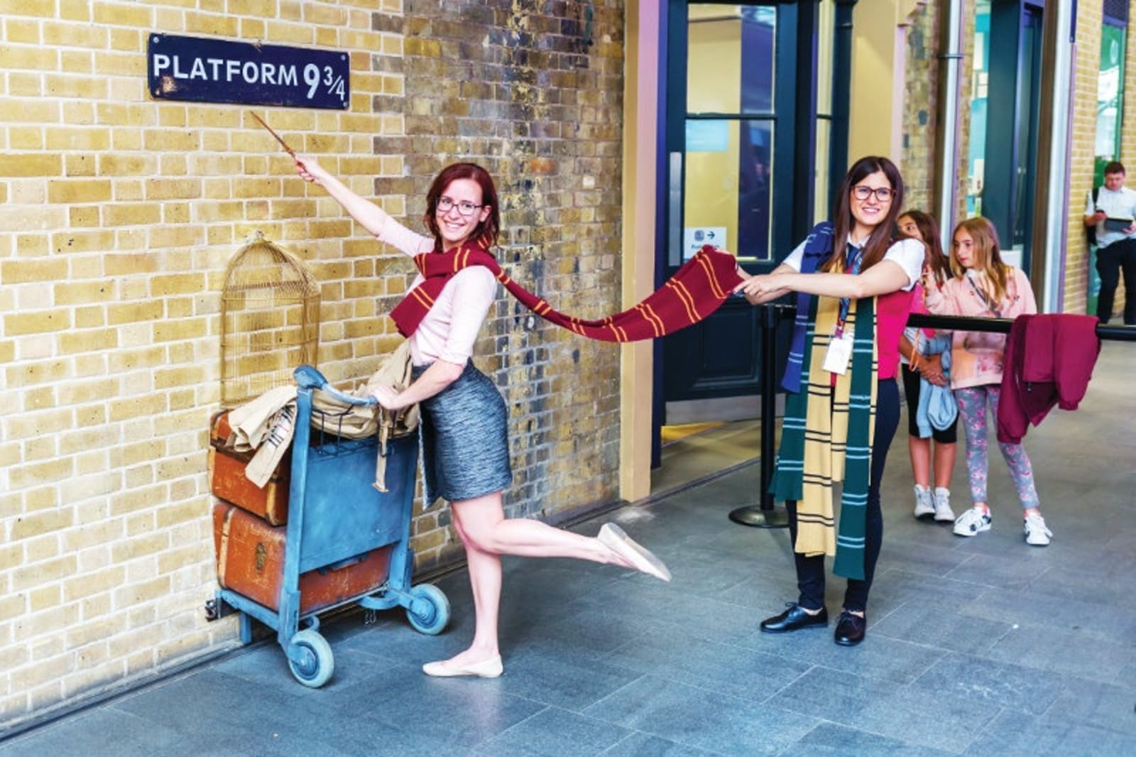 people dressed in hogwarts scarves at platform 9 3/4