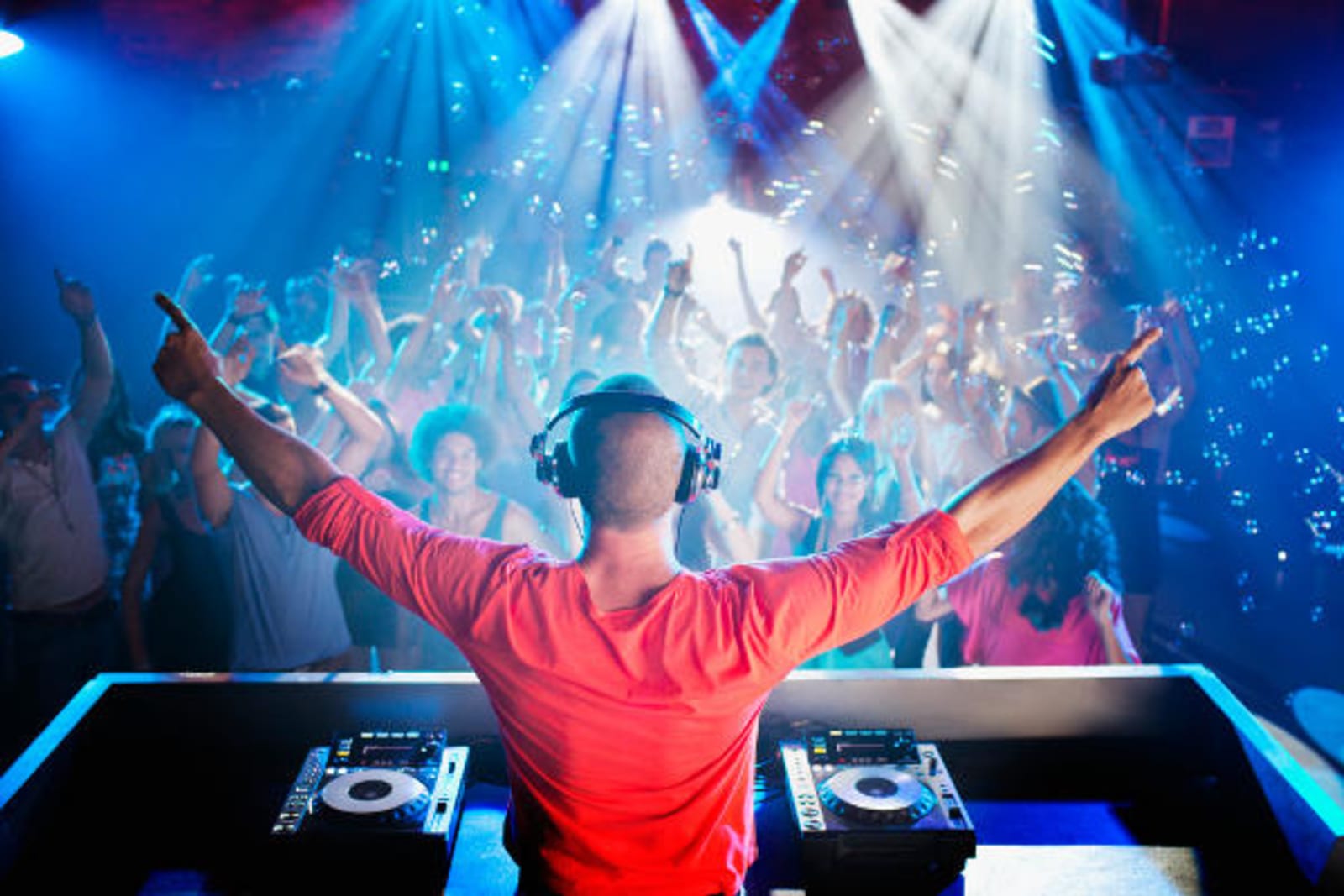DJ in a red shirt under stagelights
