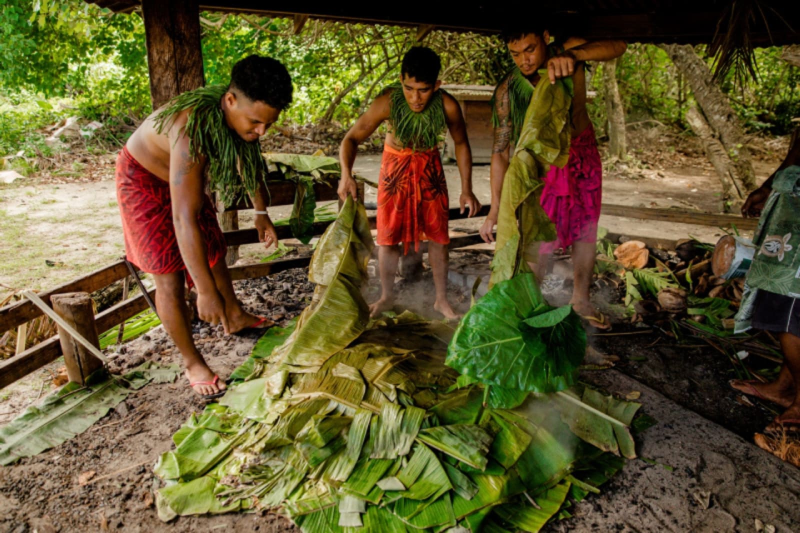 Samoan men take leaves off food cooking in umu at Coconuts Beach Club Resort in Upolu. 