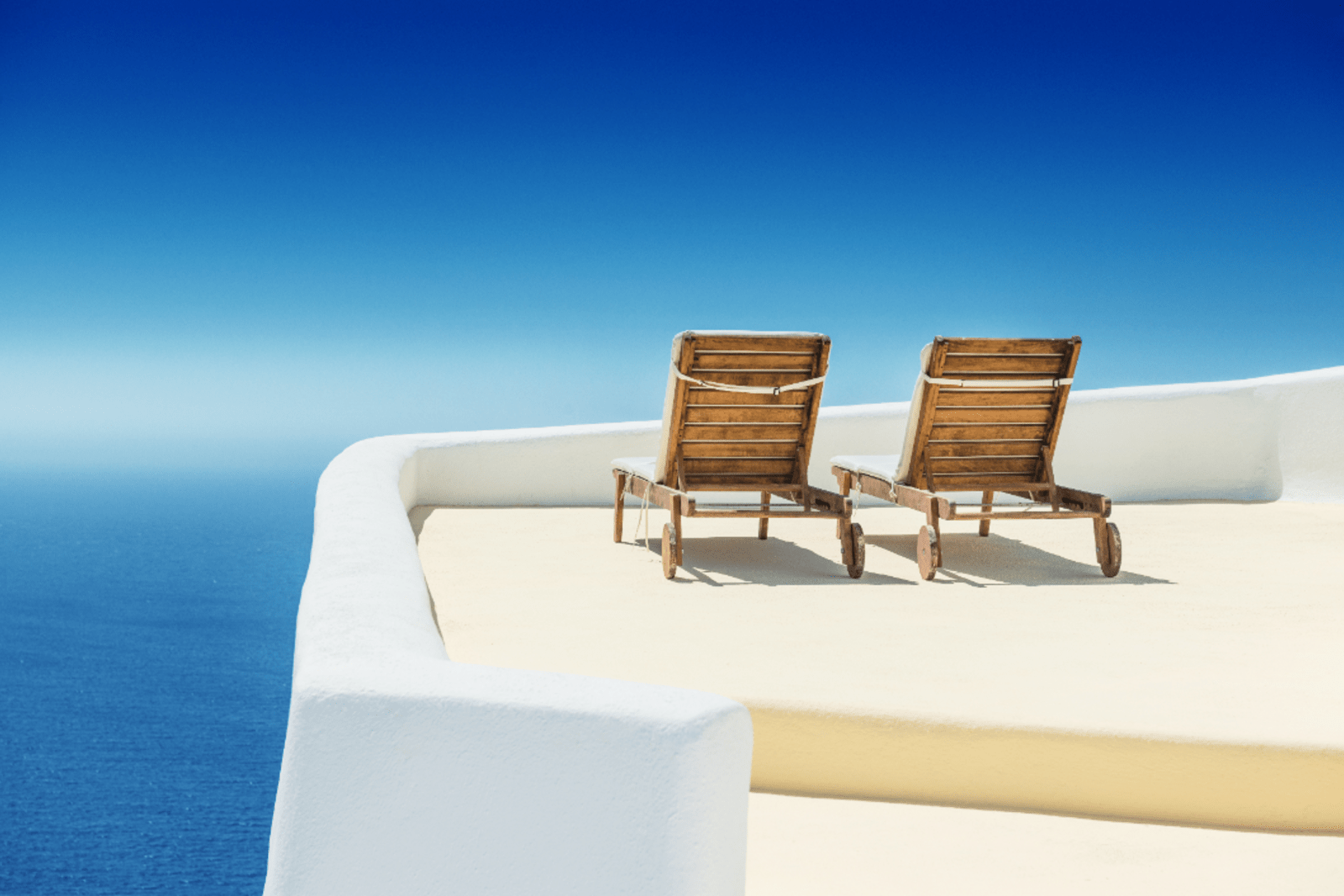 Empty sun lounge chair on balcony in Santorini