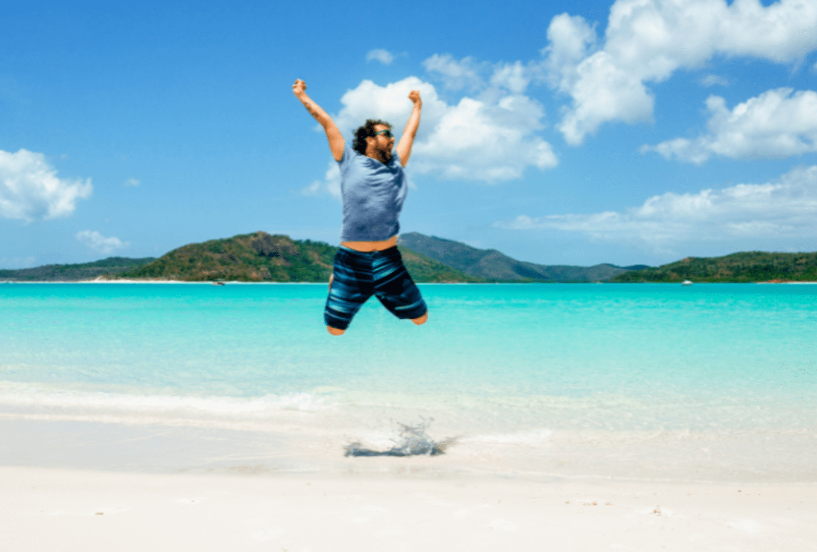 A man jumps for joy on Whitehaven Beach, Whitsunday Island