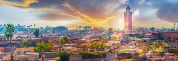 View of marrakesh city with sun shining behind clouds in the background