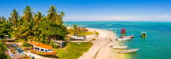 A beach located in Seychelles that has several boats on land as well as on the shore line