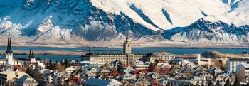 Village buildings and houses with mountain covered in snow in background located in Reykjavik