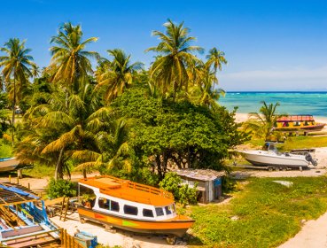 A beach located in Seychelles that has several boats on land as well as on the shore line