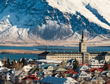 Village buildings and houses with mountain covered in snow in background located in Reykjavik