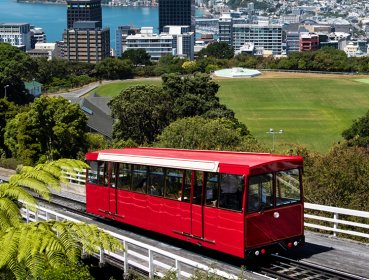 Single cart red train on track with CBD of Wellington is in the background
