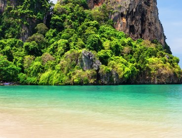 Wide angle shot of canoe half on shore half in water on an island beach located in Phuket