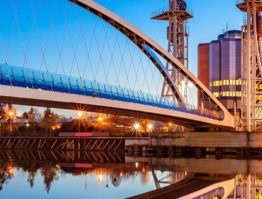 Milenium Bridge at dusk with streetlights turning on and reflecting the image in the water below