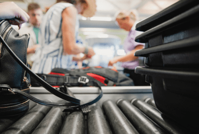 Travellers placing bags and luggage on an airport security conveyor belt