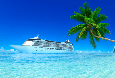 A cruise ship at anchor in sparkling clear water adjacent to a Pacific island beach