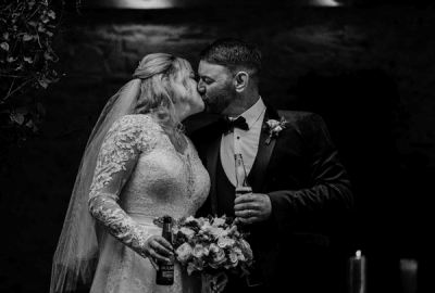 Bride (Geraldine) and Groom (Tom) kiss holding drinks at their wedding in Dublin 