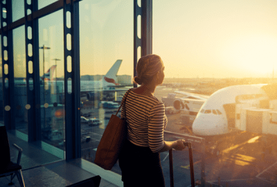 A young woman looking through the window of an airport departure lounge