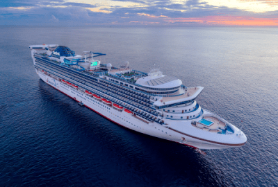 Carnival cruise ship sailing across calm ocean waters during a colourful sunset